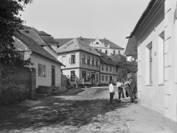 Zruč nad Sázavou, ulice s lidmi a obchodem, v pozadí škola, negativ 12,9 x 17,8